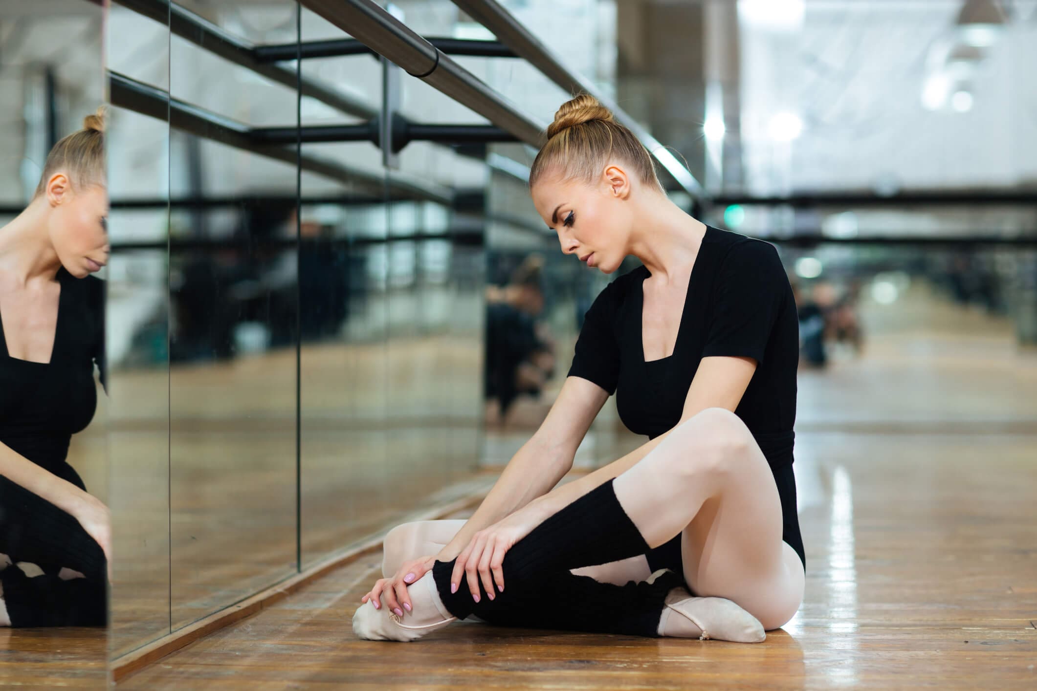 njured ballerina in pointes sitting on the floor in ballet class