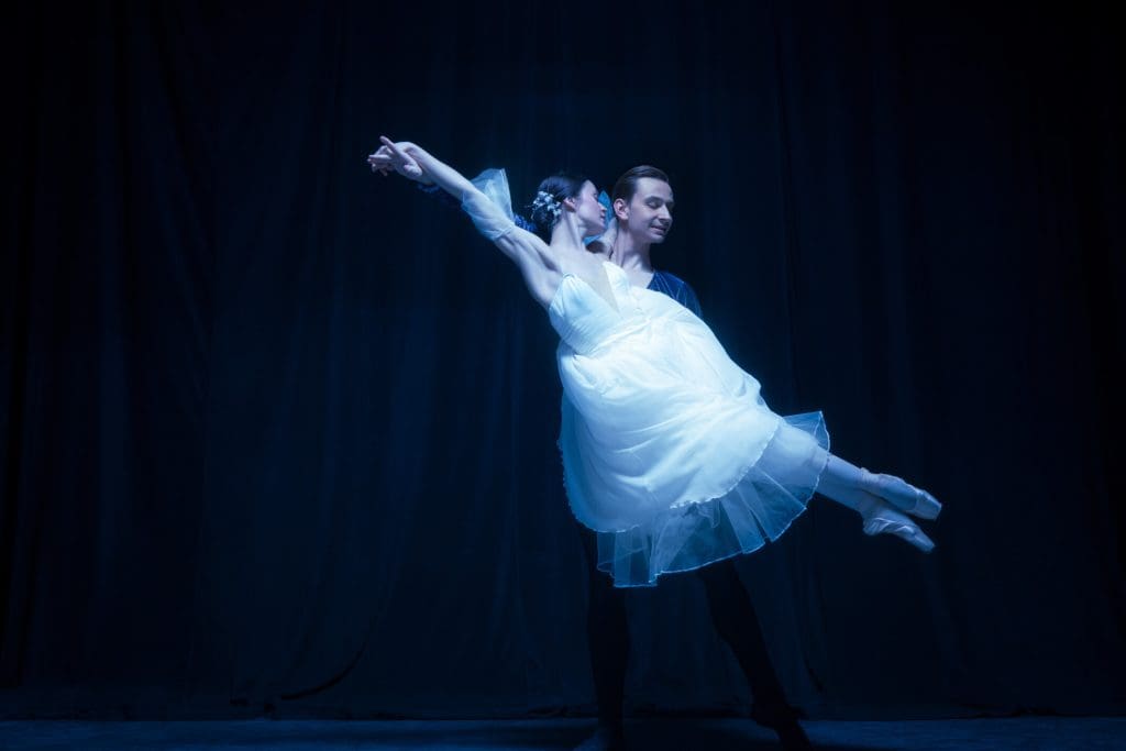 Graceful balerina in image of ghost bride with patner in art ballet performance isolated over dark background. Concept of love, relationship, beauty, art and theater. Copy space for ad.
